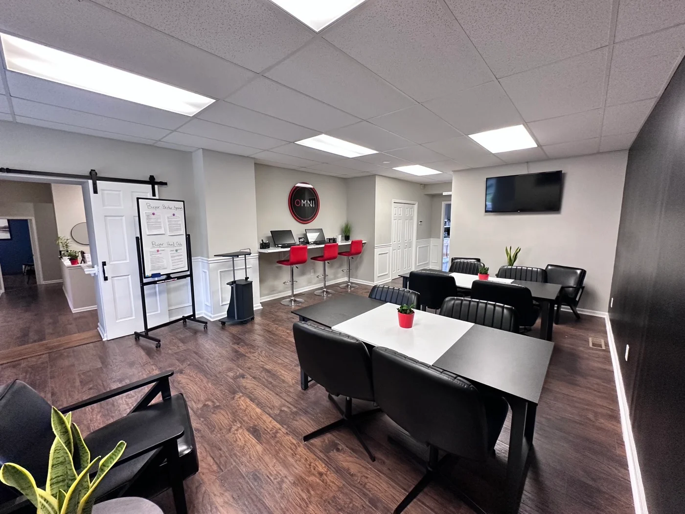 OMNI Real Estate Professionals training bar with displays, red stools, and the OMNI ring mark
